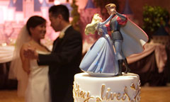 Bride and Groom Dance in View of Cake Topper of Cinderella Dancing with Her Prince