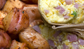 A breakfast burrito with a side of potatoes.