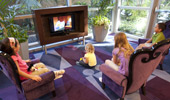 4 kids are focused on a Disney cartoon in the TV viewing area of the Disneyland Hotel lobby.