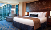 King-size bed next to view of blue-tinged glass that envelops the reinterpreted Resort hotel.