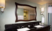 The elegant bathrooms have black granite counters and a large mirror framed by dark wood.