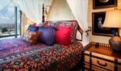 Bed with brightly colored pillows and spread.