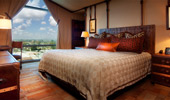 Large bed, surrounded by steamer trunk tables and Adventureland artwork.
