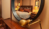 Reflection of bed and surroundings framed in a mirror.