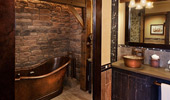 Old-time free standing tub, vanity and artwork reflected in bathroom mirror.