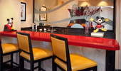 A red bar with yellow high chairs, a Mickey telephone and a Mickey statue.