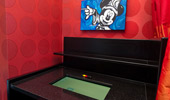 A tablet is embedded in a writing desk that sits beneath a painting of Sorcerer Mickey.