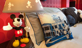 A decorative Mickey-themed throw pillow is positioned next to a Mickey bedside lamp.