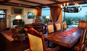 Flat-screen TV over a faux fireplace in the living area and carved wood table in dining area.