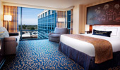 King-size bed next to view of blue-tinged glass that envelops the reinterpreted Resort hotel.