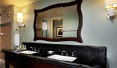 The elegant bathrooms have black granite counters and a large mirror framed by dark wood.