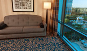 A stylish sofa sits near a window and beneath a framed collage of images from Disneyland history.