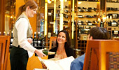 A server pours champagne for a seated couple.