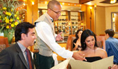 A server assists a woman with her order by pointing to a popular menu selection.