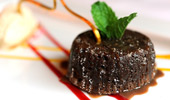 Close up of a decadent chocolate dessert topped with fresh mint leaves