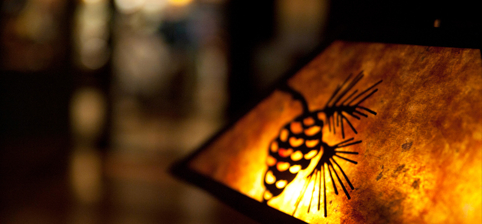 Close up on a lit lamp shade with an an acorn detail
