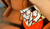 View from above of seating area with armchair, ottoman and Arts and Crafts-style table and lamp.