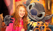 A girl poses for photos with the Disney Character Stitch.