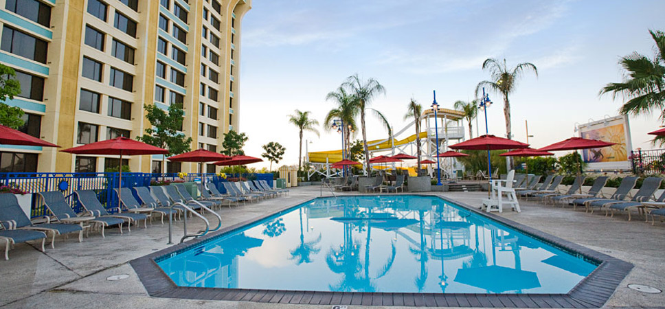 A calm pool surrounded by lounge chairs, with water slides in the background