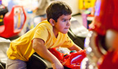 A boy rides a motorcycle-themed arcade game.