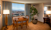 Beneath a large window that frames the view is a wood table and 2 chairs.