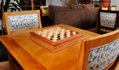The wood table by the window has a matching wood checkers and chess board.