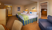 In the room: 2 queen-size beds, a large sleeping sofa, a large cabinet with dresser drawers and space for television.