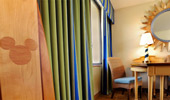 A surfboard-inspired drink table sits near bright blue and green curtains and a sun-yellow computer table.