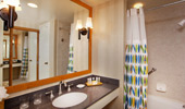 The shower curtain with surfboard design is reflected in the bathroom mirror.
